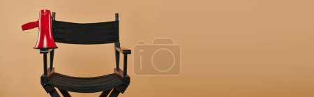 chaise de réalisateur avec un mégaphone rouge sur fond beige, cinématographie et bannière de production