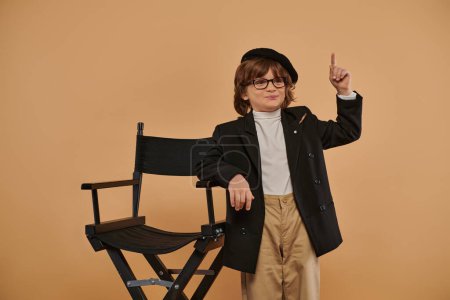 happy boy standing near director chair, with a smile on face showing idea sign,  profession