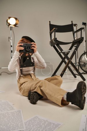 niño captura el momento en la cámara mientras está sentado rodeado de guion y silla de director