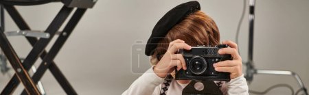 Photo for Boy in beret captures the moment on retro camera, horizontal banner of young photographer - Royalty Free Image