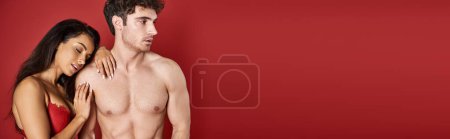 Photo for Sensual young woman with brunette hair leaning on body of muscular man on red background, banner - Royalty Free Image