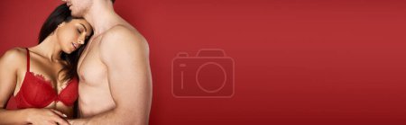 Photo for Beautiful young woman in sexy lace lingerie embracing muscular boyfriend on red background, banner - Royalty Free Image
