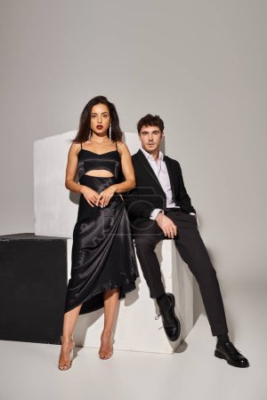 Valentines day concept, attractive young couple in evening wear posing near cubes on grey background
