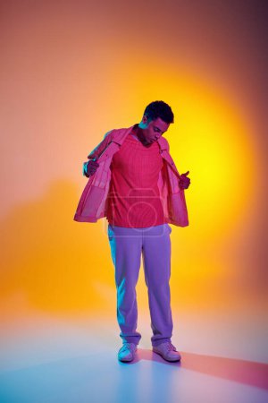 Elegante hombre afroamericano posando en ropa de moda y casual con un vibrante fondo degradado