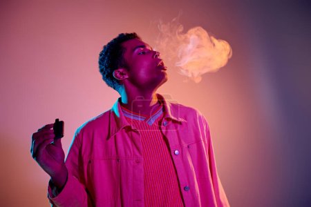 Porträt eines afrikanisch-amerikanischen Mannes, der Rauch ausatmet, während er E-Zigarette auf buntem Hintergrund hält