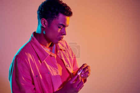 Photo for African american man rolling cigarette for smoking on vibrant background with blue neon lighting - Royalty Free Image
