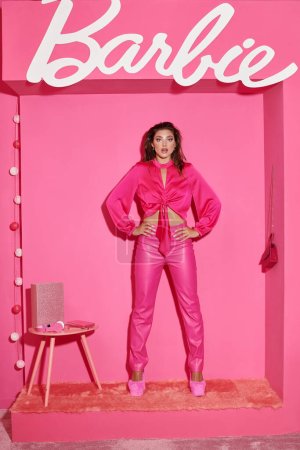 Téléchargez les photos : KYIV, UKRAINE - 14 JUILLET 2023 : Poupée étonnante comme une femme en haut de culture et pantalon rose debout avec les mains sur les hanches dans la chambre rose, Barbie - en image libre de droit