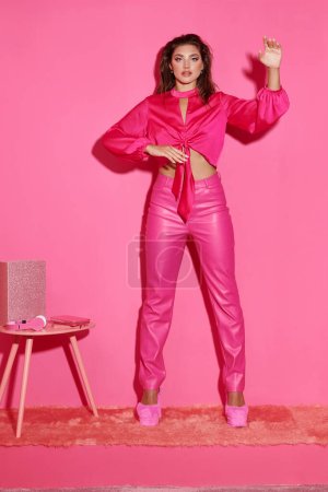 hübsche junge Frau in bauchfreiem Top und pinkfarbener Hose gestikuliert unnatürlich und verhält sich wie eine Puppe