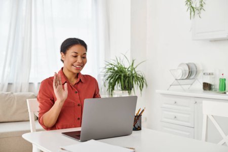 nutricionista afroamericana feliz que proporciona consulta en línea en el ordenador portátil de su cocina