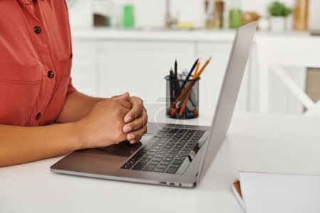cropped african american woman using laptop while working from her modern kitchen, nutritionist