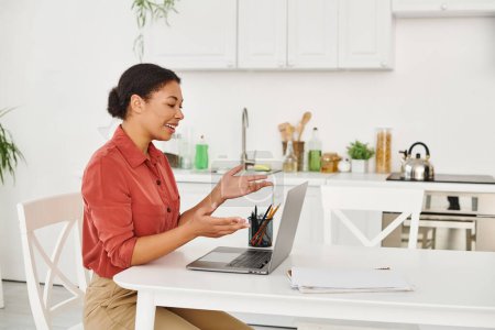 happy african american female nutritionist providing consultation on laptop from her kitchen