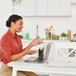 happy african american female nutritionist providing consultation on laptop from her kitchen