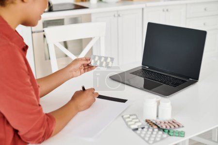 cropped nutritionist writing prescription near medication during online consultation on laptop