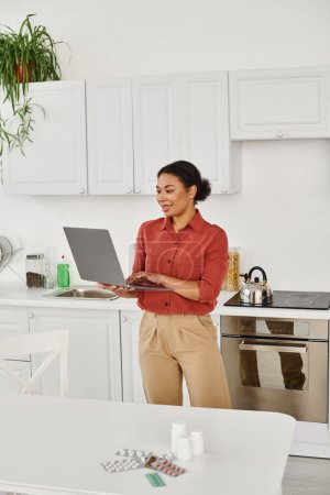 cheerful african american dietitian giving consultation on laptop near  different medication on desk