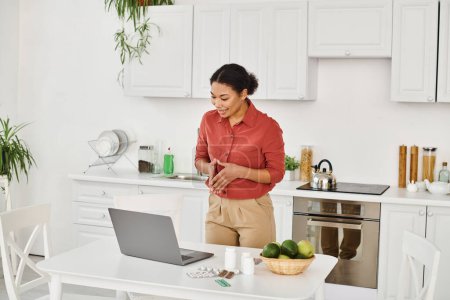 Afrikanisch-amerikanische Diätassistentin gestikuliert, während sie neben Laptop steht und online Ernährungsberatung anbietet