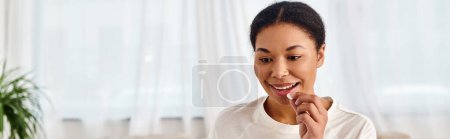 bannière de femme afro-américaine heureuse prenant la pilule à la maison, parfaite pour la santé et le bien-être
