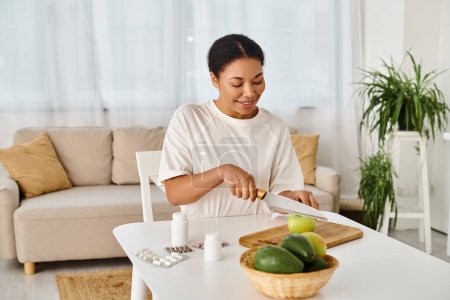 heureux afro-américain nutritionniste compare les suppléments avec des fruits pour une alimentation saine à la maison