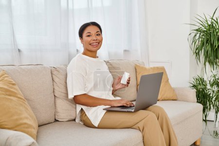 heureux afro-américain nutritionniste avec des suppléments donnant des conseils alimentaires en ligne à partir d'un ordinateur portable