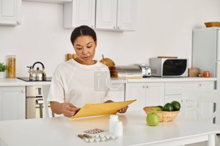 brünette afrikanisch-amerikanische Frau öffnet Umschlag mit Ernährungsplan in der Nähe von Nahrungsergänzungsmitteln und Früchten