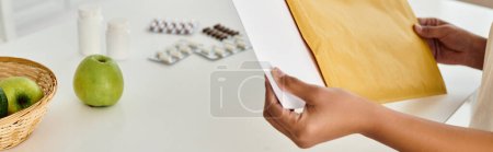 Photo for Cropped banner of woman reviewing dietary plan near supplements and fruits on kitchen table - Royalty Free Image