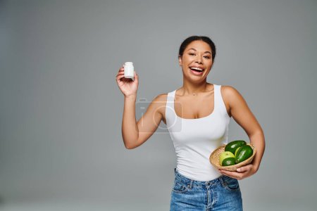 dietista afroamericano feliz con frutas verdes y suplementos que muestran un estilo de vida saludable