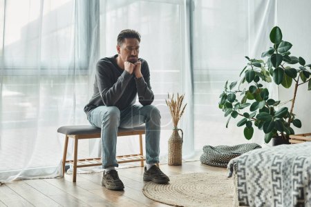 Photo for Upset bearded man in casual home wear sitting on bedroom bench and looking away, depression - Royalty Free Image