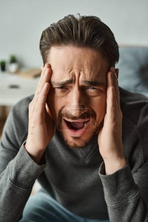 Photo for Bearded man feeling sharp pain and frowning while screaming and looking at camera, migraine - Royalty Free Image