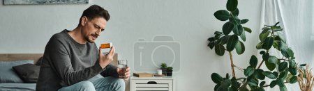 banner of bearded man holding glass of water while looking at medication and sitting on bed