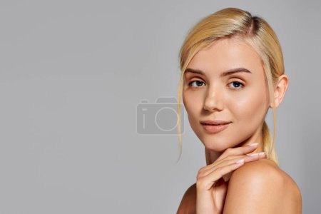 Photo for Beauty woman looking with gentle gaze and touching shoulder with slight smile in gray background - Royalty Free Image