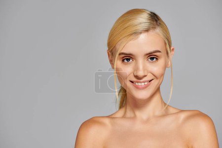 beauty young woman with grey eyes looking forward and smiling broadly against in gray background