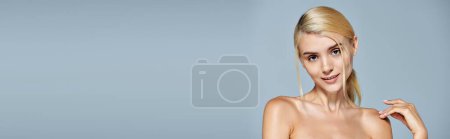 banner of pretty woman smiling lightly and touching shoulder with hand in gray background