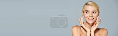 Photo for Horizontal view of smiling woman with hands around her face looking to side in gray background - Royalty Free Image