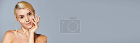 Foto de Estandarte de mujer rubia bonita aplicación juguetona crema con mirada confiada sobre fondo gris - Imagen libre de derechos