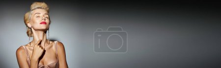 Photo for Horizontal banner of blonde girl with red lips and long earrings posing on grey background - Royalty Free Image