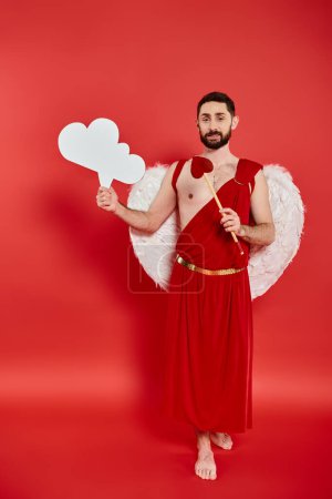 bearded cupid man with white empty thought bubble and hear-shaped arrow on red, full length