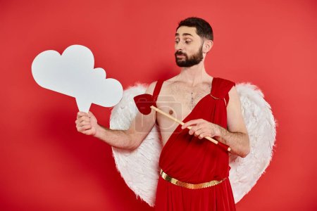 pensive cupid man with heart-shaped arrow looking at white empty thought-bubble on red backdrop