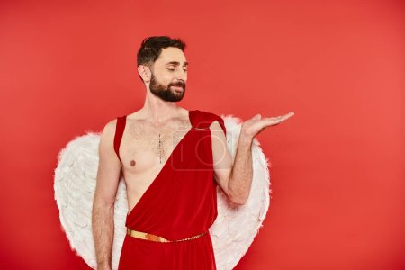 smiling bearded cupid man pointing with hand with open palm on red, st valentines costume party