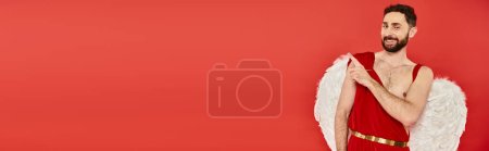 funny bearded cupid man looking at camera and pointing away with finger on red, horizontal banner