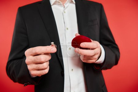 cropped view of wealthy man with gift box and jewelry ring on red, Saint Valentines day present