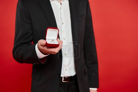 cropped view of successful elegant businessman with ring in jewelry box on red, st valentines gift