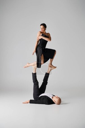 Dynamic duo of two acrobats performing balance act in a studio setting with grey background