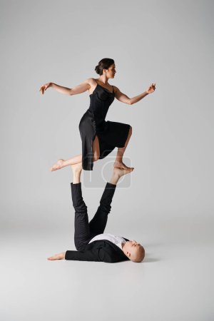 Dynamic duo, couple of acrobats performing balance act in a studio setting with grey background