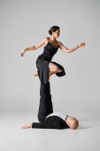 Dynamic duo, couple of acrobats performing balance act in a studio setting with grey backdrop hoodie #693347936