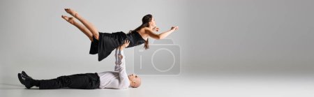 Foto de Bailarina masculina acostada en el suelo y levantando el cuerpo de la mujer vestida durante la actuación de baile, pancarta - Imagen libre de derechos