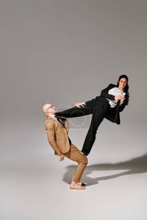 jeune femme d'affaires en utilisant smartphone et équilibrage avec l'aide de l'homme acrobate en costume en studio