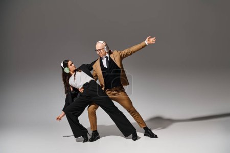 Foto de Acróbatas en trajes con auriculares inalámbricos bailando en un estilo de descanso de oficina, manos extendidas - Imagen libre de derechos