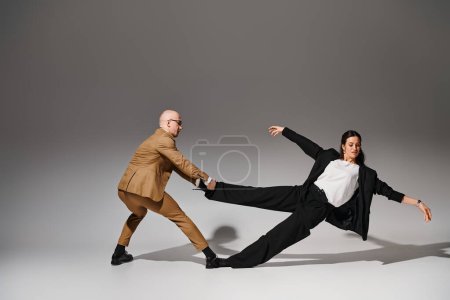 Dynamic dancers in business attire performing a balancing act in a studio with grey background