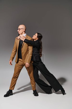 Corporate Paar in Business-Kleidung Durchführung eines Tanzes im Studio auf grauem Hintergrund, Unterstützung