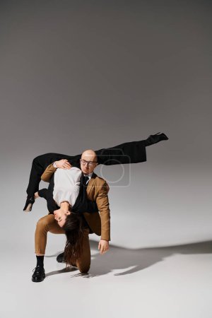 Business partners in a coordinated dance move, woman balancing upside down with support of man