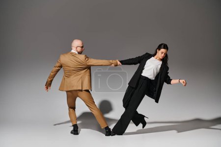 Tanzpartner in formeller Kleidung halten Händchen während des Auftritts im Studio mit grauem Hintergrund